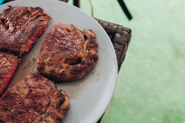 Mezzo appetitoso bistecca alla griglia fresca media arrostito sul piatto bianco circondato da erba verde