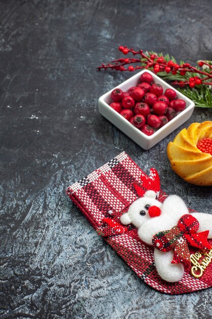 Mezzo colpo di delizioso biscotto accessorio per la decorazione del calzino di Babbo Natale e del cornell in una ciotola con rami di abete su superficie scura dark