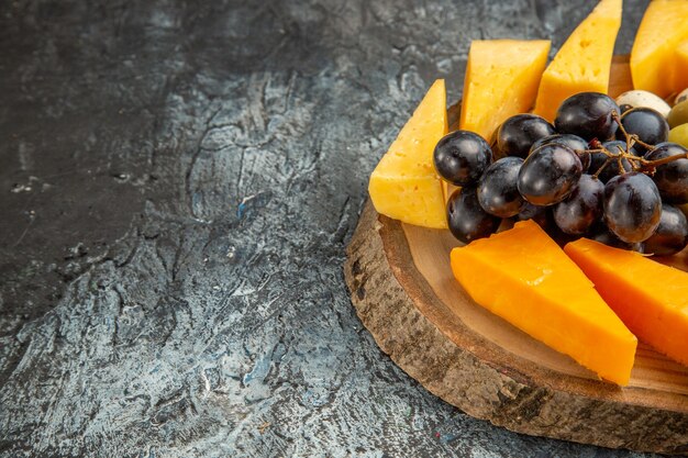 Mezzo colpo di delizioso spuntino con frutta e cibi su un vassoio marrone sul lato sinistro su sfondo di ghiaccio