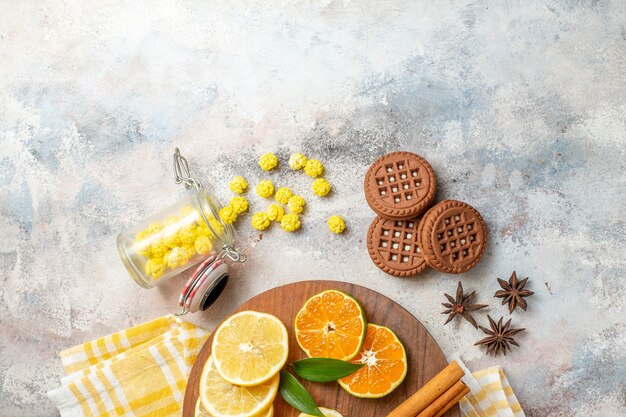 Mezzo colpo di fettine di limone e calce cannella su un tagliere di legno e biscotti sul tavolo bianco