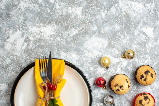 Mezzo colpo di posate per il pasto su un piatto bianco e accessori per la decorazione piccoli cupcakes sulla superficie del ghiaccio