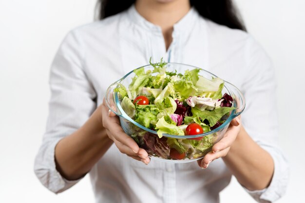 Mezzo sezione della ciotola della tenuta della donna di insalata vegetariana sana