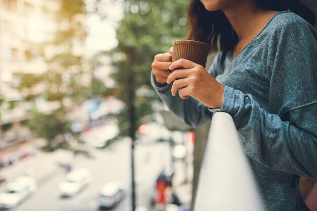 Mezzo sezione della donna che beve tè che sta sul balcone