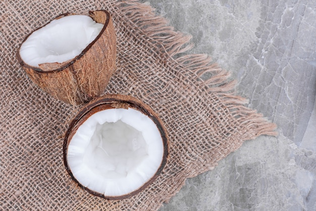 Mezzo taglio di cocco fresco e sano posto sulla superficie della pietra.