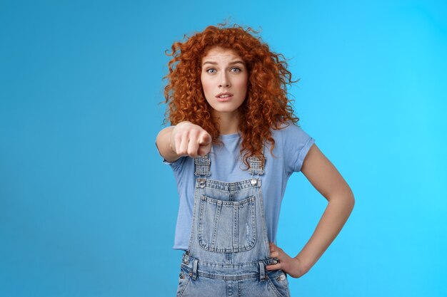 Mi sembri familiare. Preoccupato preoccupato vivace rossa emotiva ragazza riccia che punta la telecamera guarda eccitato riconoscere nervosamente qualcuno in piedi confuso tenere la mano in vita indossare tute. Copia spazio