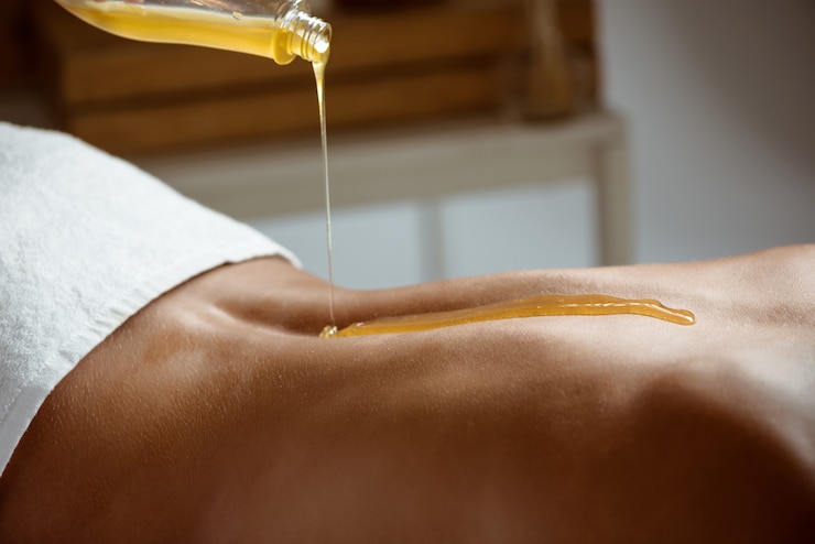 Foto gratuito miele che versa sulla schiena nuda di donna nel salone spa.