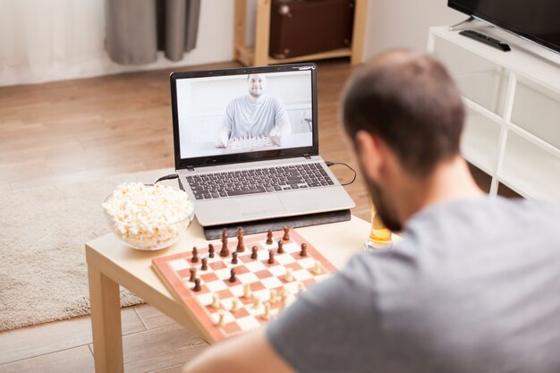 Migliori amici che giocano a scacchi durante una videochiamata in tempo di quarantena.