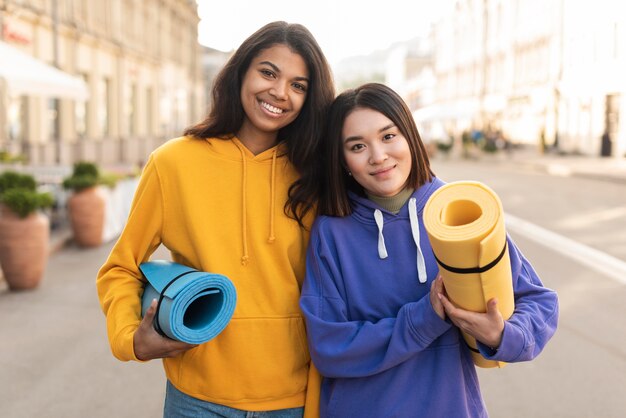 Migliori amici che tengono stuoie di fitness