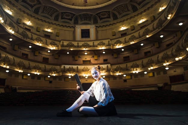 Mime femmina con manoscritto seduto nell&#39;auditorium vuoto