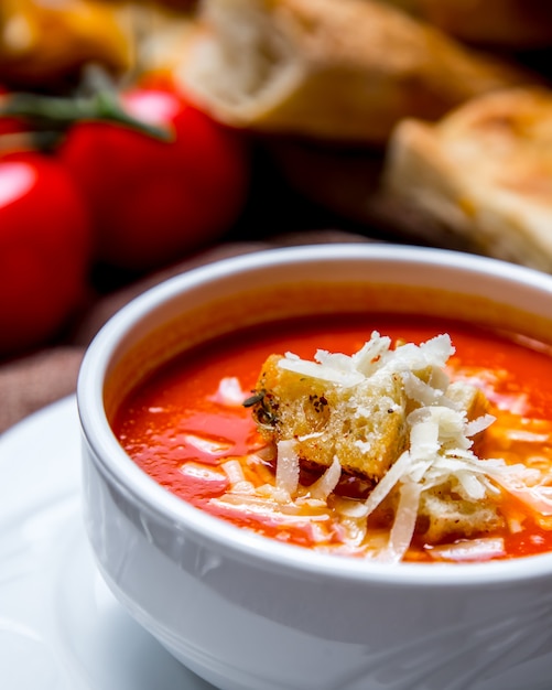 Minestra di pomodoro della fucilazione del ritratto con i cracker e pomodori e pane del formaggio sulla tavola