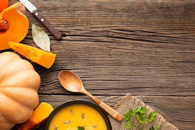 Minestra piana della zucca di disposizione in ciotola con la zucca e cucchiaio di legno con lo spazio della copia