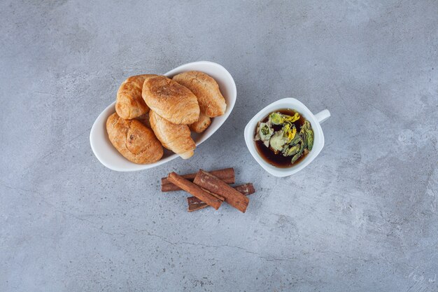 Mini cornetti di pasta sfoglia con crosta dorata e una tazza di tè.