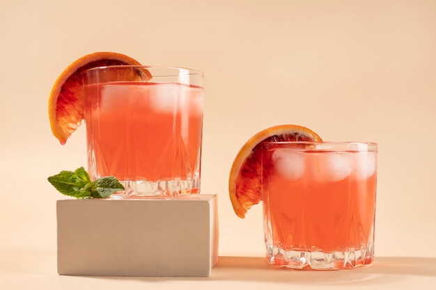 Miscela di cocktail in bicchieri con cubetti di ghiaccio e arancia rossa