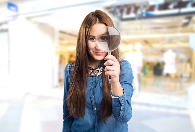 Moda giovane donna con una lente d&#39;ingrandimento di fronte al suo occhio