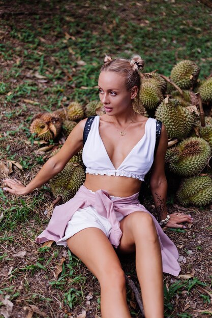 Moda giovane donna su un campo tropicale con frutti durian