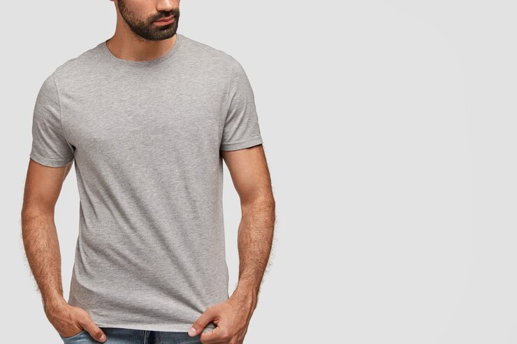 Foto gratuito moda giovane uomo barbuto in jeans e maglietta grigia oversize, pose al chiuso contro il muro bianco