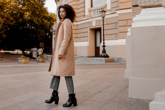 Moda immagine integrale di elegante donna di colore in elegante cappotto beige di lusso e maglione di velluto