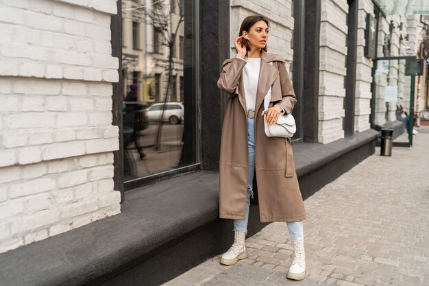 Moda ritratto di strada di elegante donna bruna europea in cappotto di pelle in posa all'aperto