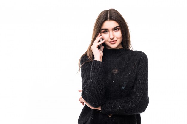 Modella in colloqui di maglione scuro sul telefono su bianco in studio