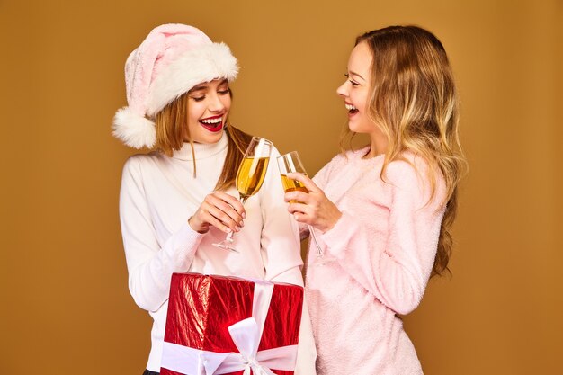 Modelli con grande confezione regalo bevendo champagne in bicchieri per celebrare il nuovo anno