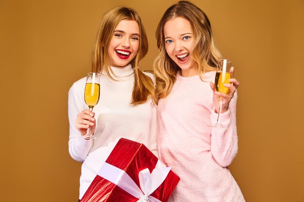 Modelli con grande confezione regalo bevendo champagne in bicchieri per celebrare il nuovo anno