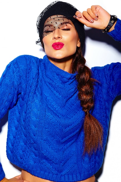 modello alla moda di bella giovane donna alla moda con le labbra rosse in panno blu dei pantaloni a vita bassa del maglione che dà bacio