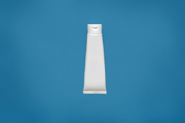 Modello bianco in bianco di progettazione del tubo isolato sul blu, percorso di ritaglio. Confezione di crema trasparente, modello. Lozione contenitore per la cura della pelle vuoto. Cura della pelle, concetto cosmetico. Gel, tubo, flacone.