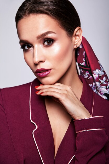 modello del brunette in vestito rosso con trucco di sera su gray