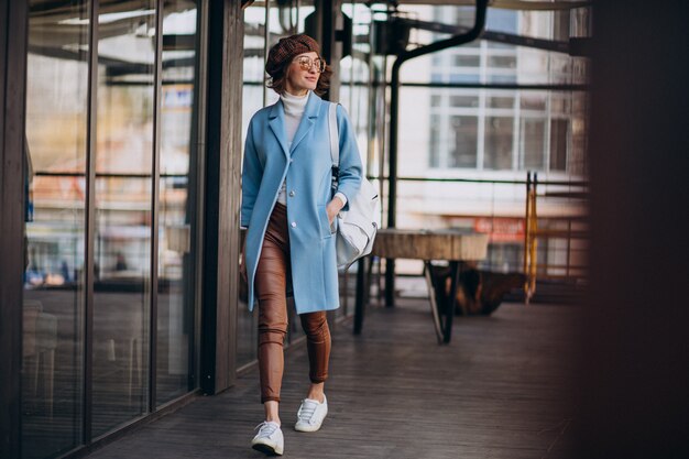 Modello della giovane donna in cappotto blu dal caffè