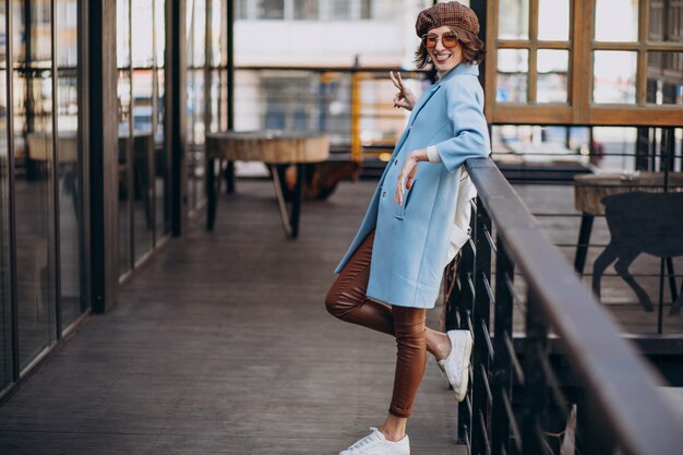 Modello della giovane donna in cappotto blu dal caffè