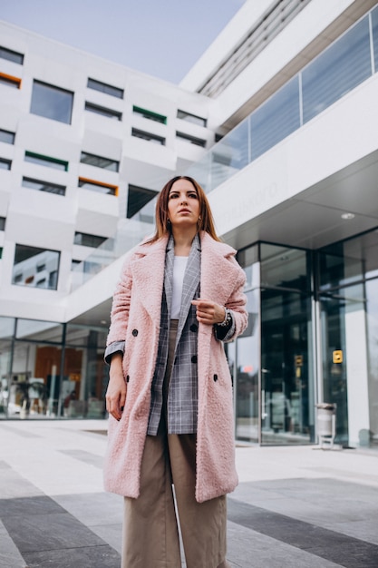 Modello della giovane donna in cappotto rosa dall&#39;edificio