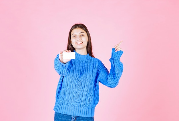 modello della ragazza che tiene una carta sulla parete rosa.