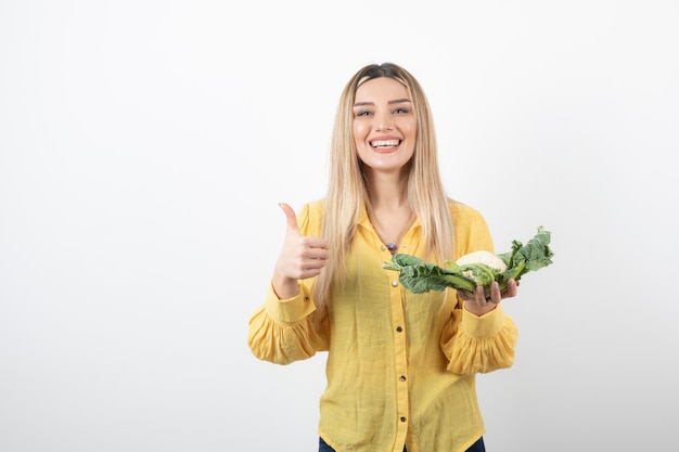 modello di donna abbastanza sorridente con cavolfiore che mostra un pollice in su.