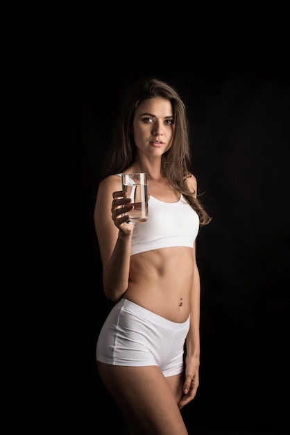 Modello di fitness femminile in possesso di un bicchiere d&#39;acqua