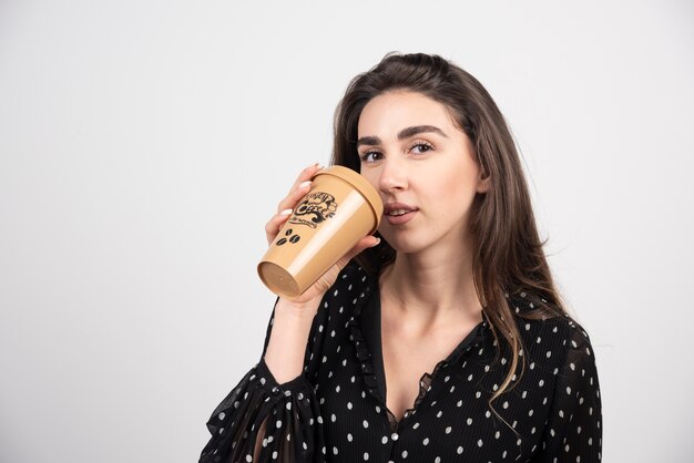 Modello di giovane donna che beve da una tazza di caffè