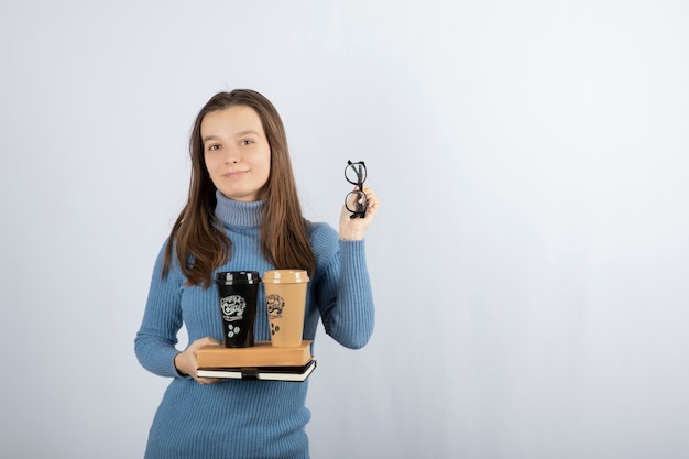 modello di giovane donna che tiene libri e due tazze di caffè.