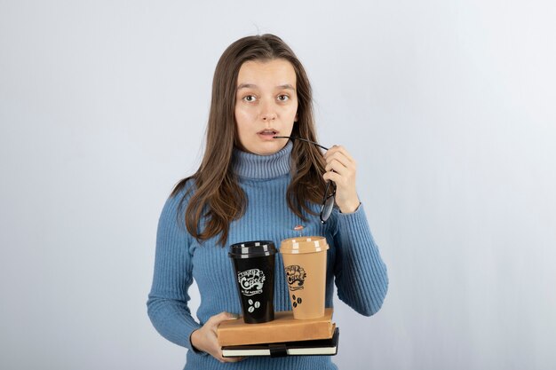 modello di giovane donna che tiene libri e due tazze di caffè.