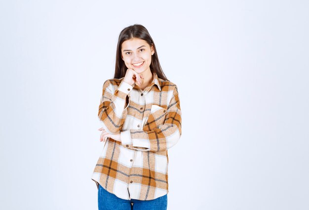 modello di giovane ragazza in piedi sul muro bianco-grigio.