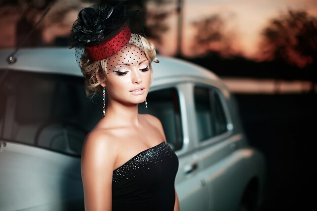 modello di ragazza bionda bella moda sexy con trucco luminoso e acconciatura riccia in stile retrò, seduto nella vecchia auto