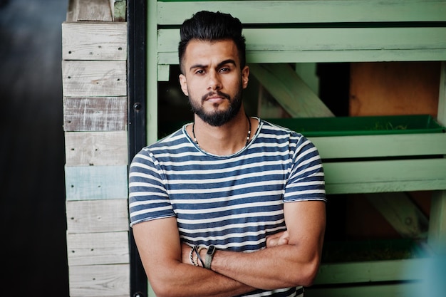 Modello di uomo bello con barba araba alta con camicia spogliata in posa all'aperto Ragazzo arabo alla moda