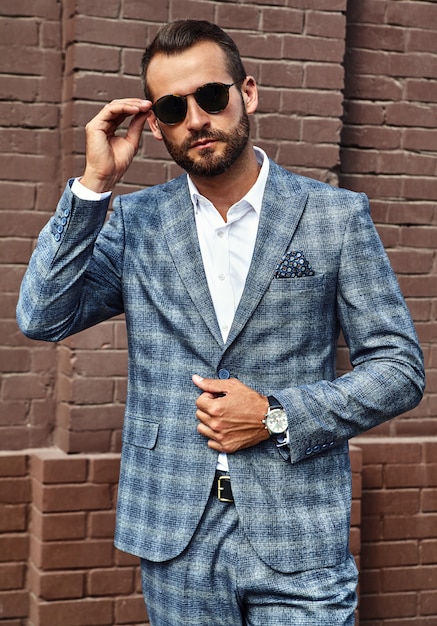 modello di uomo d'affari moda bello vestito in elegante abito a scacchi in posa sulla strada