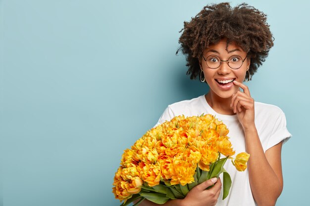 Modello femminile dalla pelle scura positiva con sguardo sorpreso felice, ha un sorriso a trentadue denti