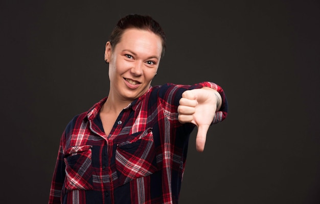 Modello femminile in abiti da collezione autunno inverno che fa pollice in giù e sorridente.