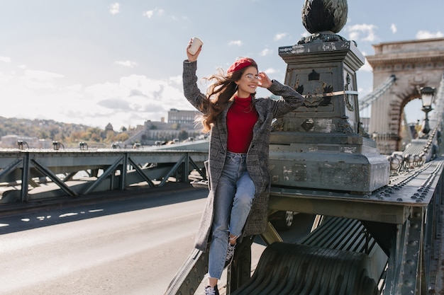 Modello femminile ispirato indossa jeans vintage che si rilassano durante il servizio fotografico sul ponte