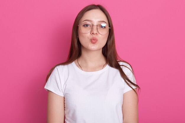 Modello femminile sbalorditivo che posa con l'espressione del fronte di bacio sul giro ottimistico