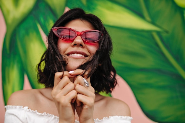 Modello femminile spensierato in posa vicino ai graffiti Vista frontale di una ragazza sensuale con occhiali da sole rosa