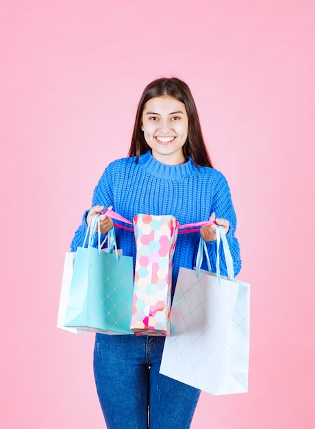 modello positivo della ragazza che tiene i sacchetti della spesa sulla parete rosa.