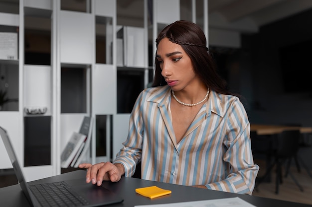 Modello queer a tiro medio che lavora con il laptop