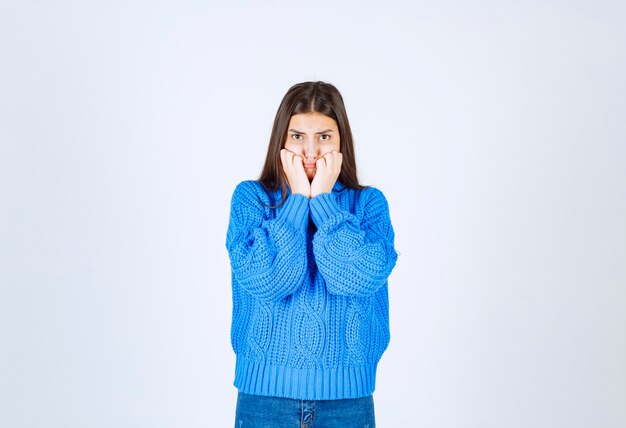 Modello ragazza preoccupata in maglione caldo che si morde le dita e guarda avanti.