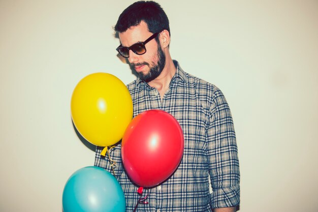 Moderno ragazzo con palloncini e occhiali da sole